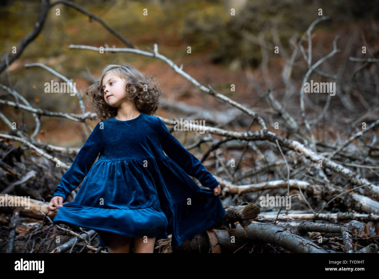 Stilvolle kind Mädchen 6-7 Jahre alt tragen Designer Blue Velvet Dress in Wald. Langsam tanzen. Kindheit. Stockfoto