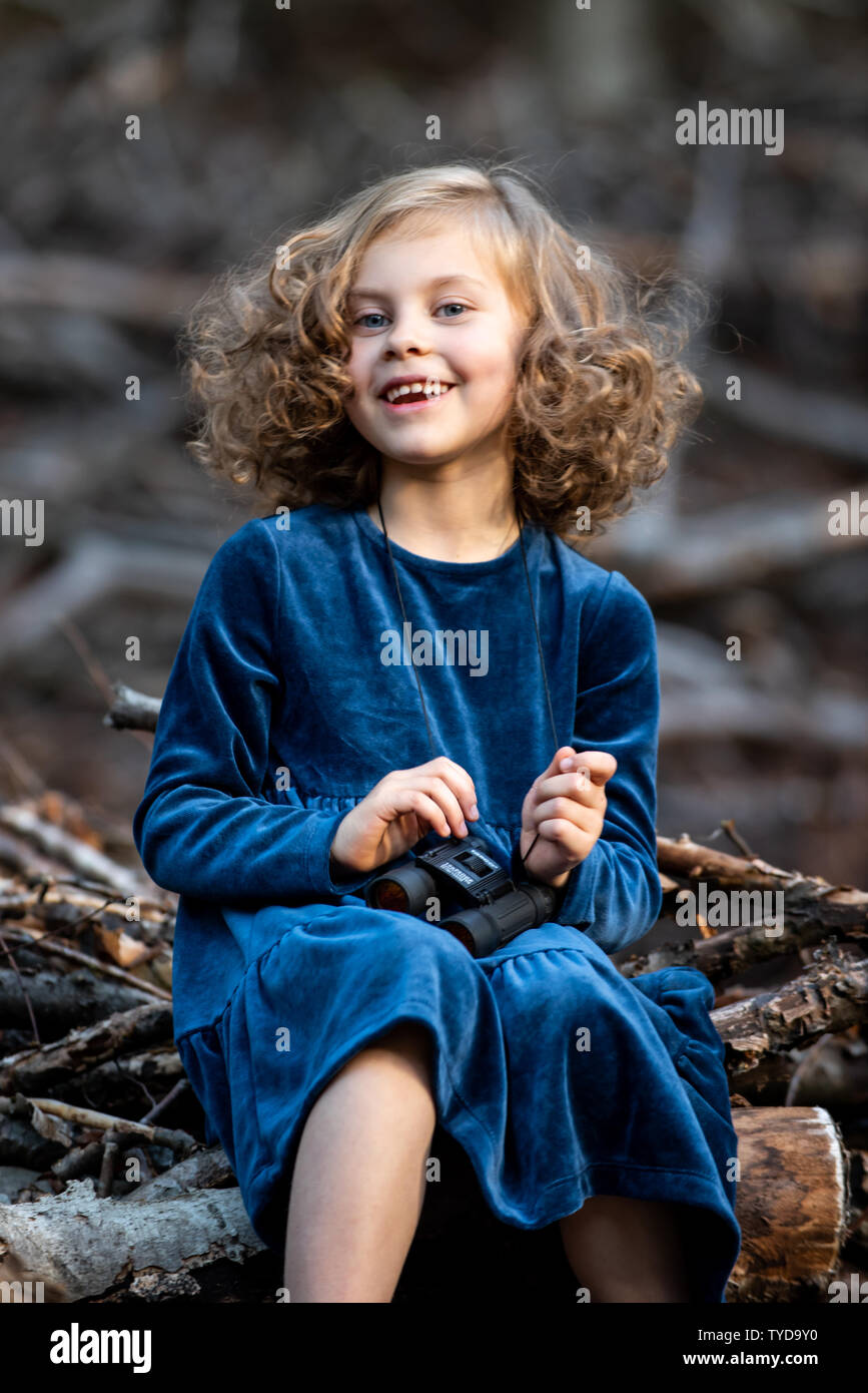 Stilvolle kind Mädchen 6-7 Jahre alt tragen Designer Blue Velvet Dress in Wald. Im Freien. Standortwahl und Kamera. Kindheit. Stockfoto