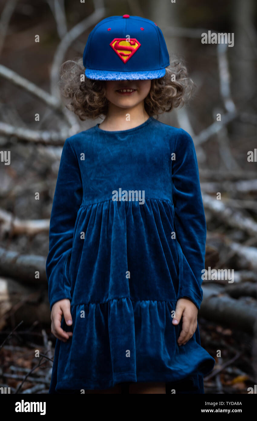 Stilvolle kind Mädchen 6-7 Jahre alt tragen Designer Blue Velvet Dress in Wald. Im Freien. Mit Blick auf die Kamera. Kindheit. Stockfoto