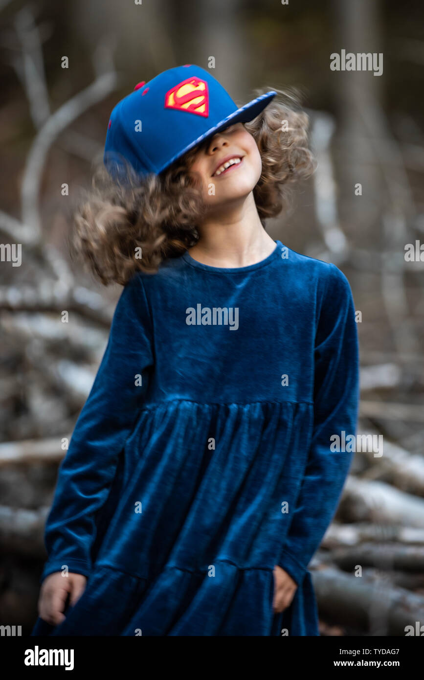 Stilvolle kind Mädchen 6-7 Jahre alt tragen Designer Blue Velvet Dress in Wald. Im Freien. Vor der Kamera. Kindheit. Stockfoto