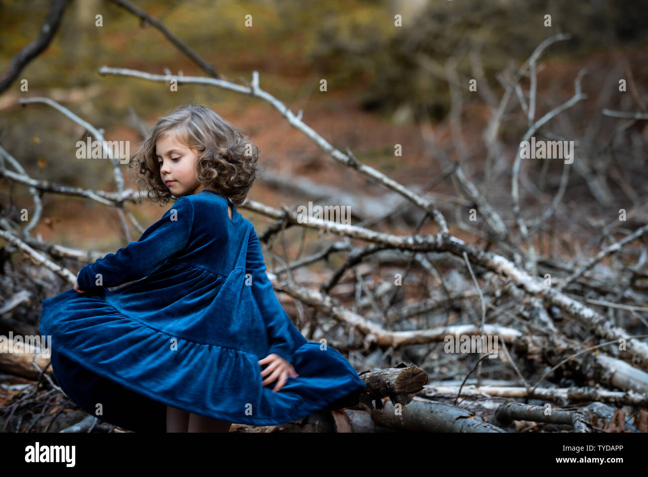 Stilvolle kind Mädchen 6-7 Jahre alt tragen Designer Blue Velvet Dress in Wald. Im Freien. Tanzen vor der Kamera. Kindheit. Stockfoto