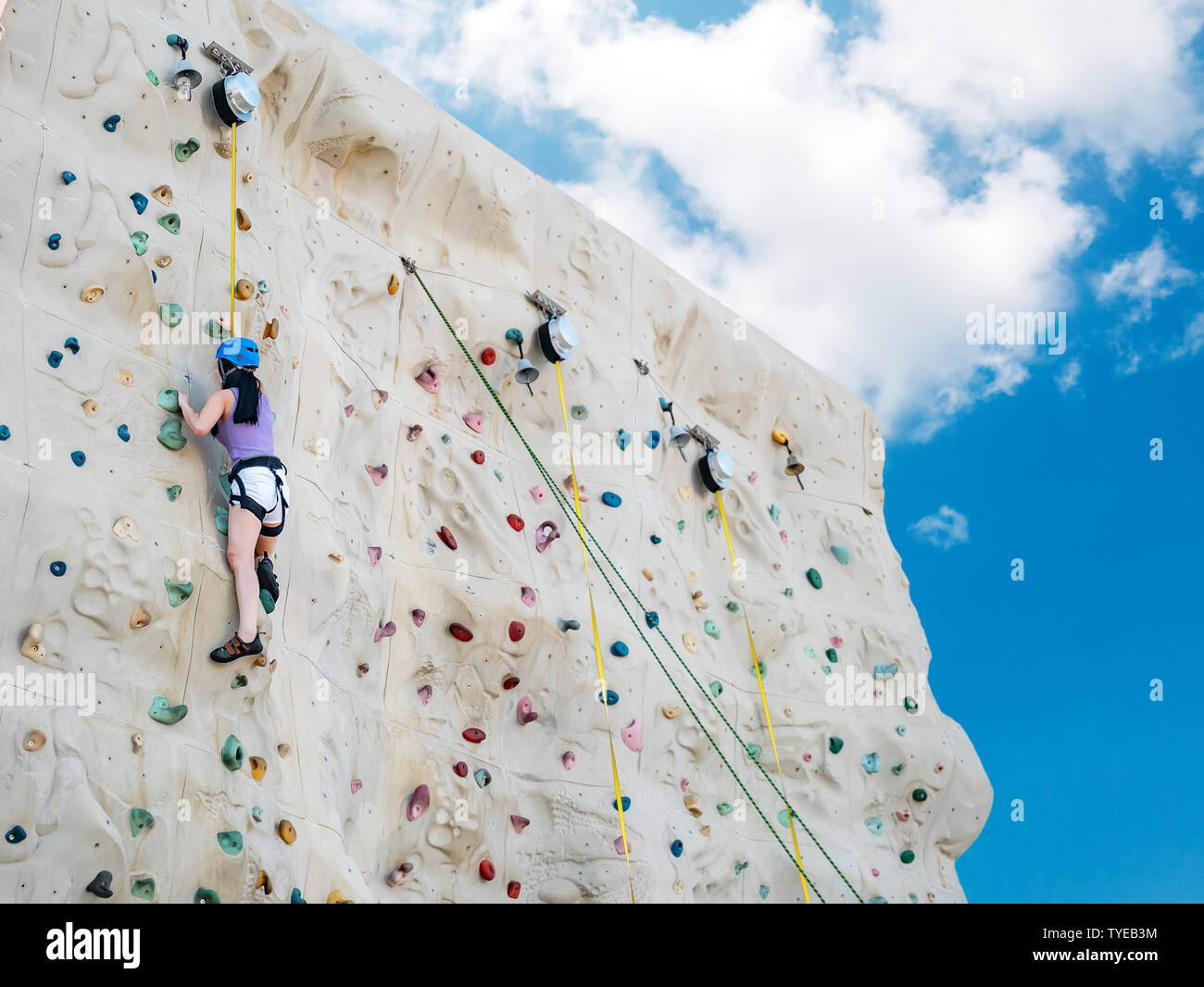 Asiatische athletische Frau üben Klettern auf einer Felswand, Outdoor Aktivität mit blauer Himmel, Low Angle View Stockfoto