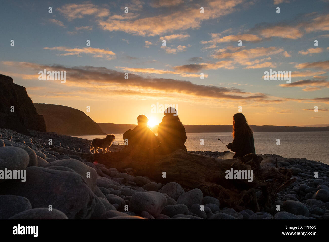 Eine Familie und genießen Sie ein Feuer bei Sonnenuntergang an den Klippen an der Küste von North Devon. Großbritannien Stockfoto