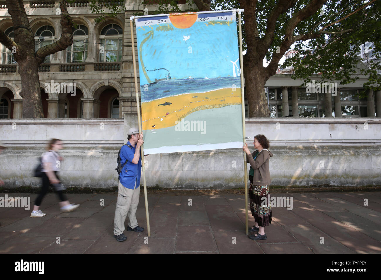 Zwei Klima Aktivisten Anzeige ein Banner mit einer Illustration von einem Strand in einer dystopischen Zukunft, auf dem Weg von der Lobby des Parlaments über Maßnahmen zum Klimawandel und Umweltschutz in Parliament Square, Westminster, London. Stockfoto