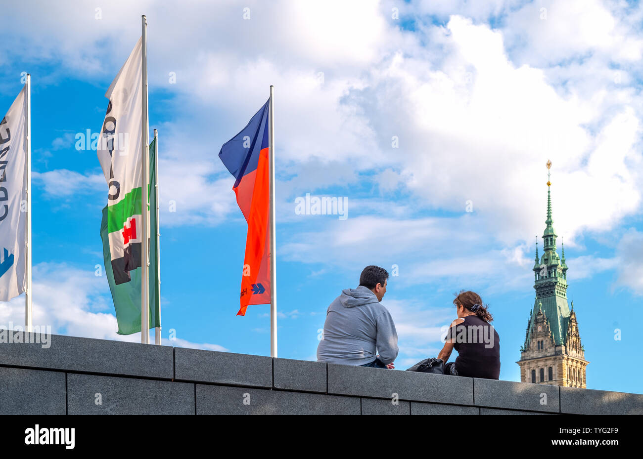 Hamburg, Deutschland - Juli 23, 2017: ein junges Paar in der Jungfernstieg stret mit Fahnen und das Rathaus Glockenturm im Hintergrund Stockfoto