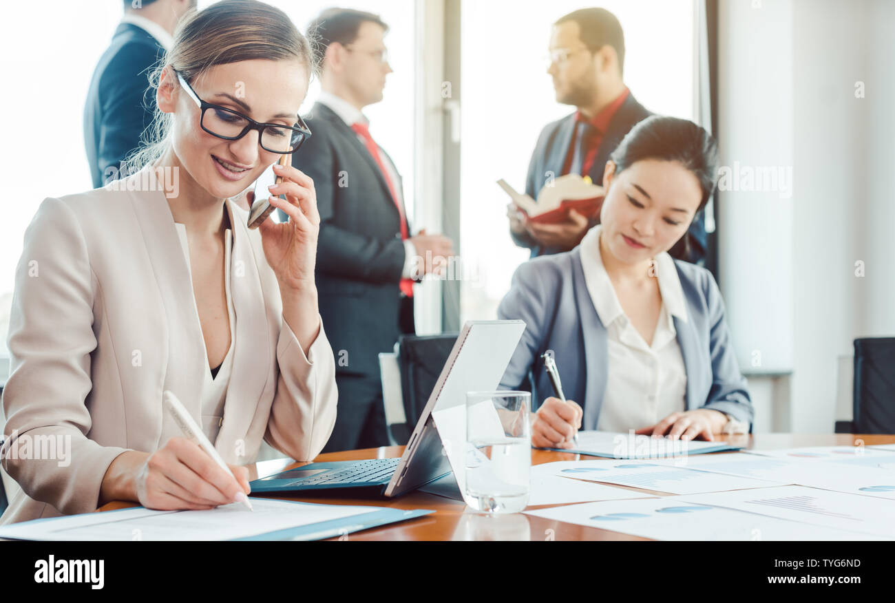 Business woman arbeiten, während die Männer untätig chatten Stockfoto