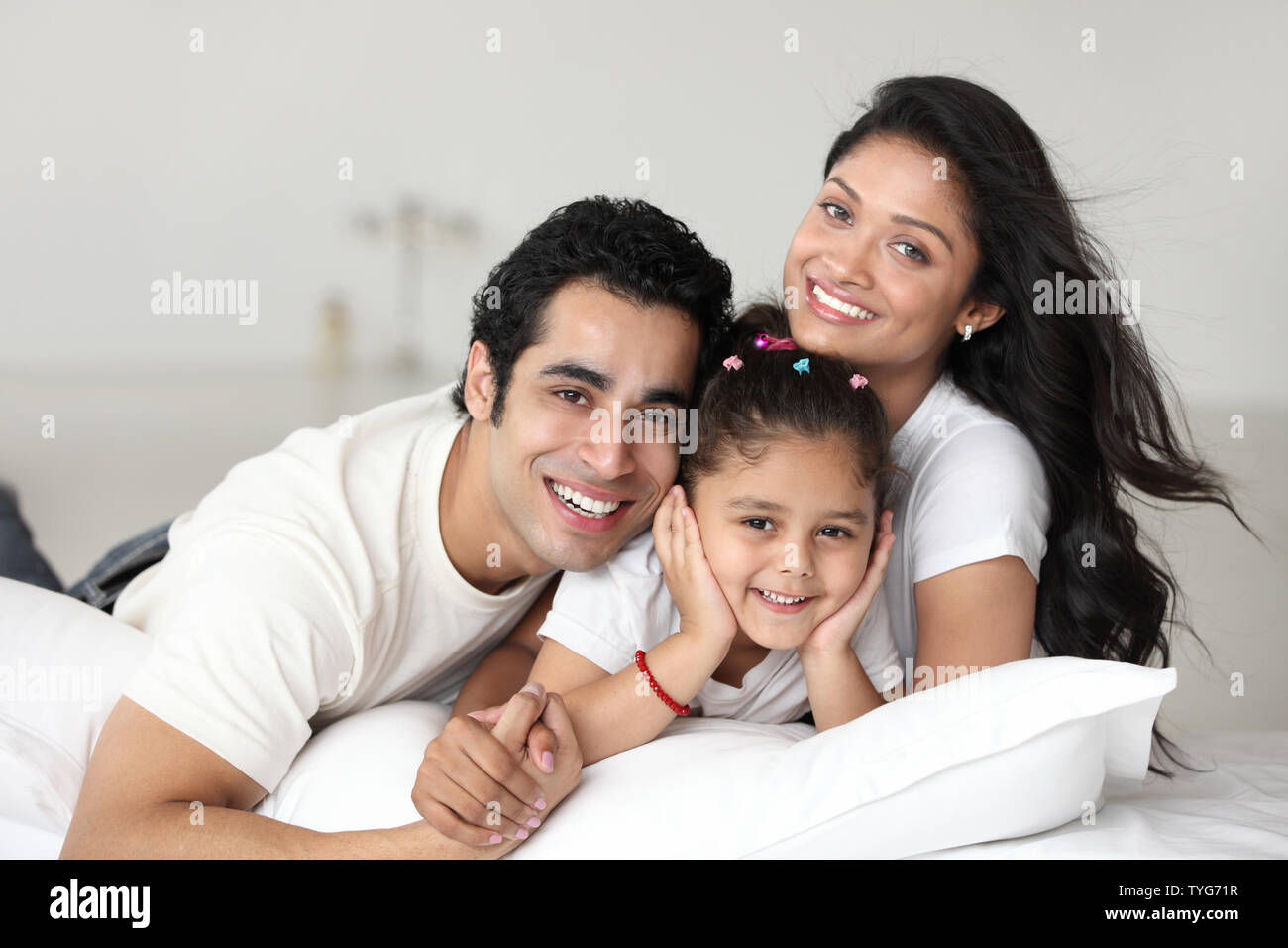 Porträt einer Familie, die lächelnd auf dem Bett Stockfoto
