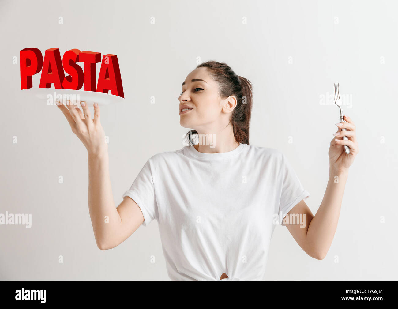 Frau in Shirt mit dem Folk isoliert auf Weiss. Weibliche Model Holding eine Platte mit Buchstaben des Wortes Pasta. Sie gesunde Ernährung, Ernährung, biologische Ernährung und Natur freundlich Lebensstil. Stockfoto