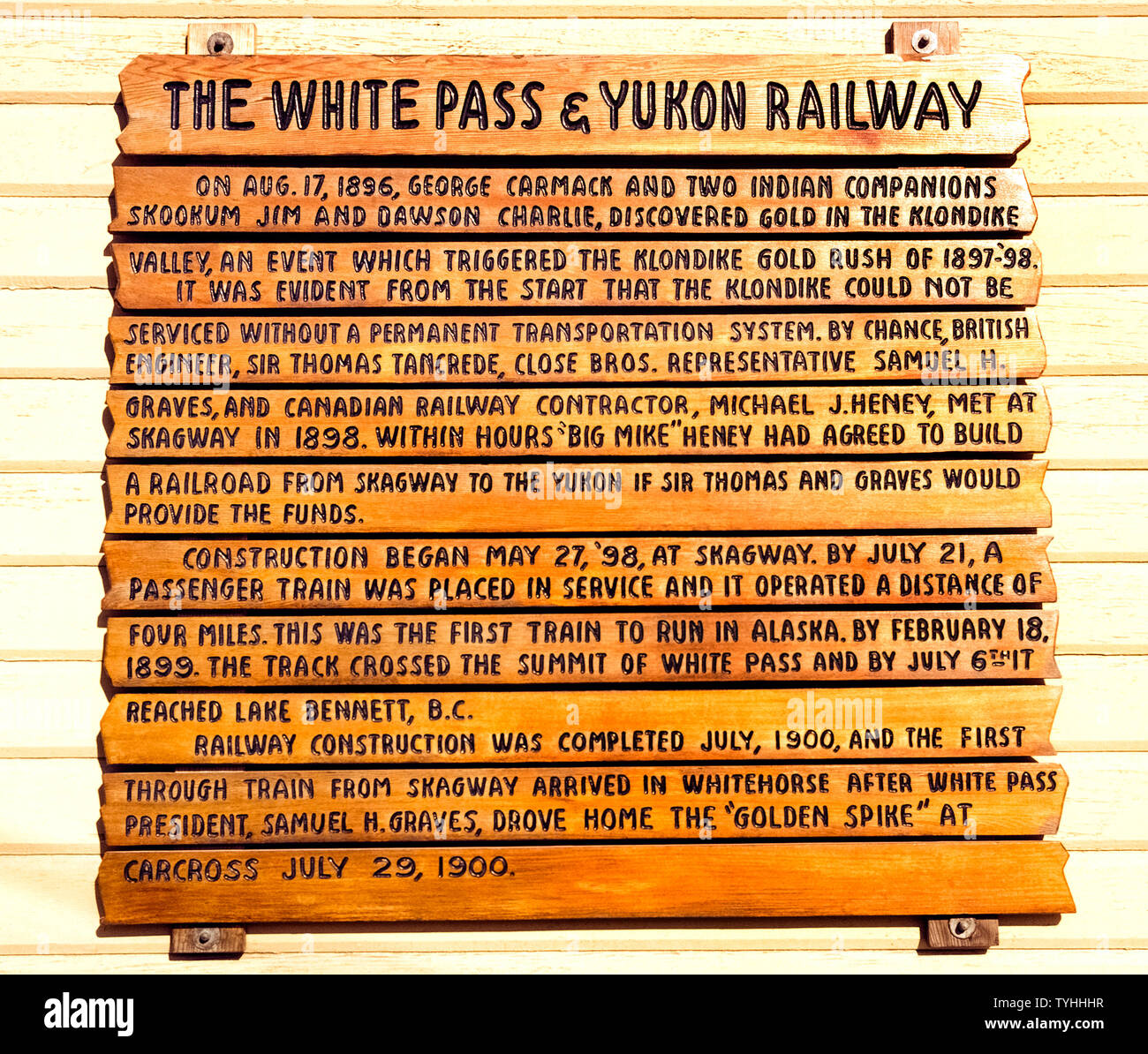 Eine hölzerne Schild gibt eine kurze Geschichte der bemerkenswerten White Pass and Yukon Railway, dass der erste Zug in Alaska, USA angeboten und wurde wegen der Gold Rush von 1897-98 zu den Klondike im Yukon Territory in Kanada gebaut. Das Zeichen ist in Skagway, Alaska, wo Prospektoren der Zug vom Meeresspiegel bis zu den 2.915 zu klettern an Bord angezeigt - Fuß (888 Meter) Gipfel des White Pass und Ihre 600 verkürzen - Meile (960 Kilometer) Trek zu den Goldfeldern. Heute Touristen Fahrt in Vintage WP&Y-Personenwagen die Route auf den Gipfel des White Pass zurückzuverfolgen und atemberaubende Landschaft genießen. Stockfoto