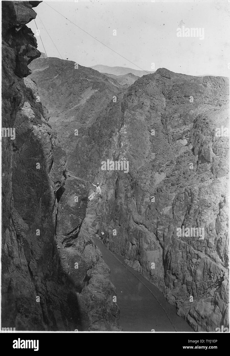 Rigger - rodman Arbeiten mit Topographie Umfrage Partei in Black Canyon in Nevada Seite. Rodman ist über Canyon Rim am Seil abgesenkt und gibt Punkte, die mit sowohl der horizontale als auch der vertikale Winkel zwischen zwei transit Parteien erfasst werden.; Umfang und Inhalt: Foto aus Band 2 einer Reihe von Fotoalben dokumentiert den Bau des Hoover Dam, Boulder City, Nevada. Stockfoto