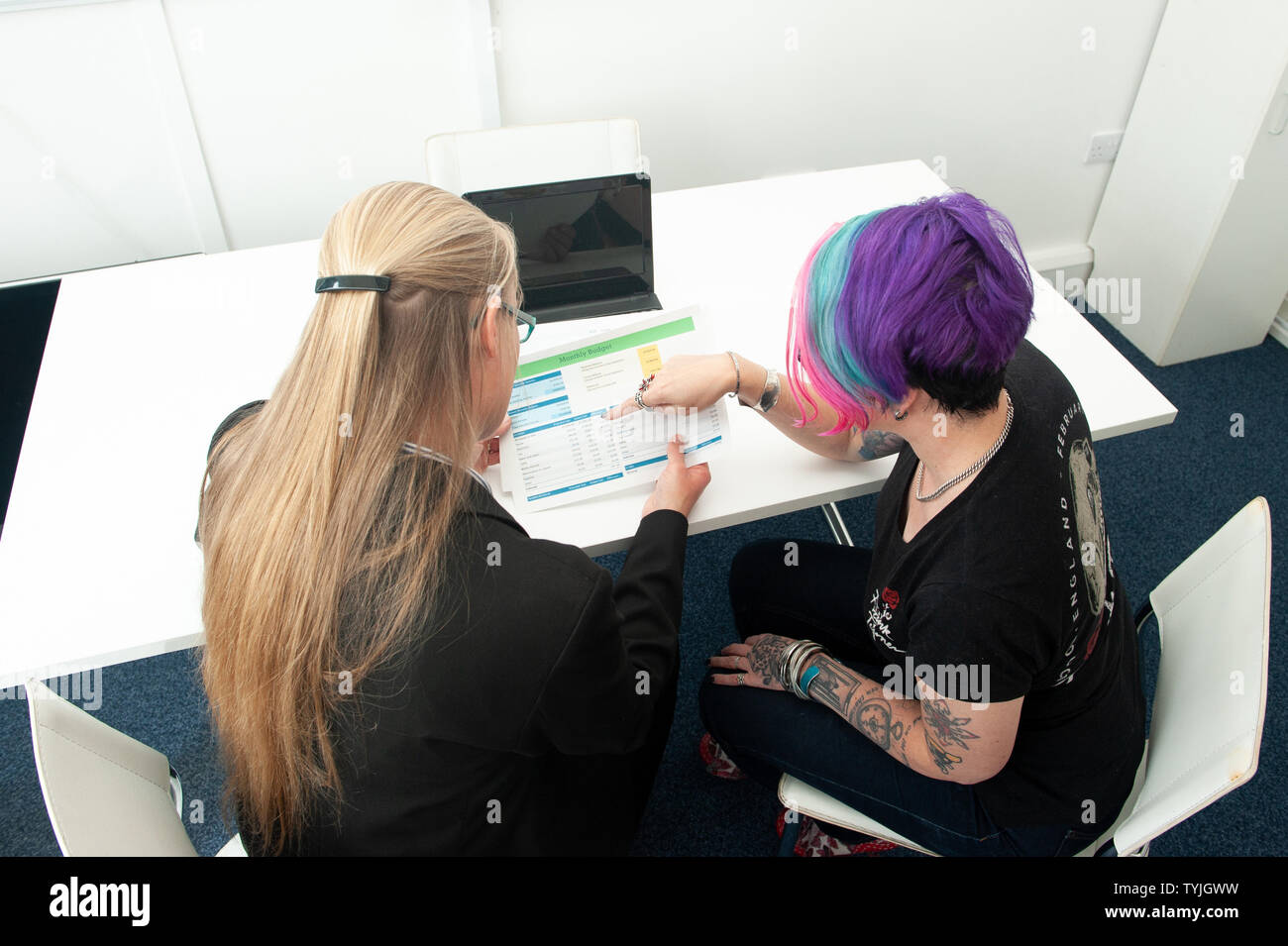 Zwei Frauen in der Diskussion um den Papierkram mit Laptop Stockfoto