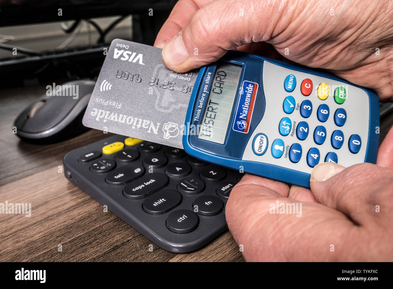 Man Hände mit bundesweiten Bank Card Reader und Visa Debit Card, mit 'Karte' auf dem Display, neben Computer Tastatur, für on-line-Transaktion. Stockfoto