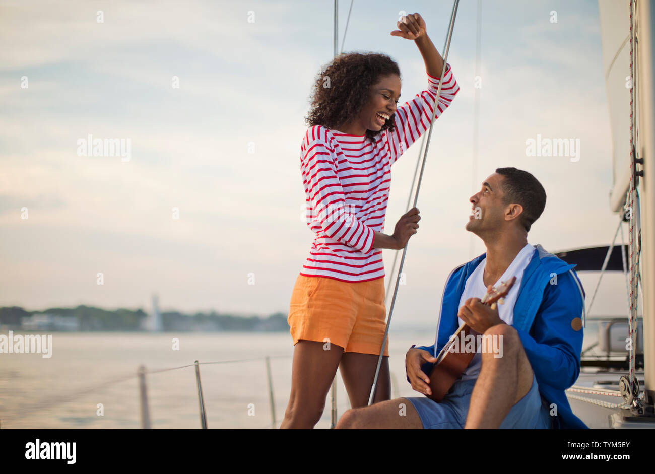 Glückliches junges Paar, das Spaß spielen der Ukulele beim Segeln. Stockfoto