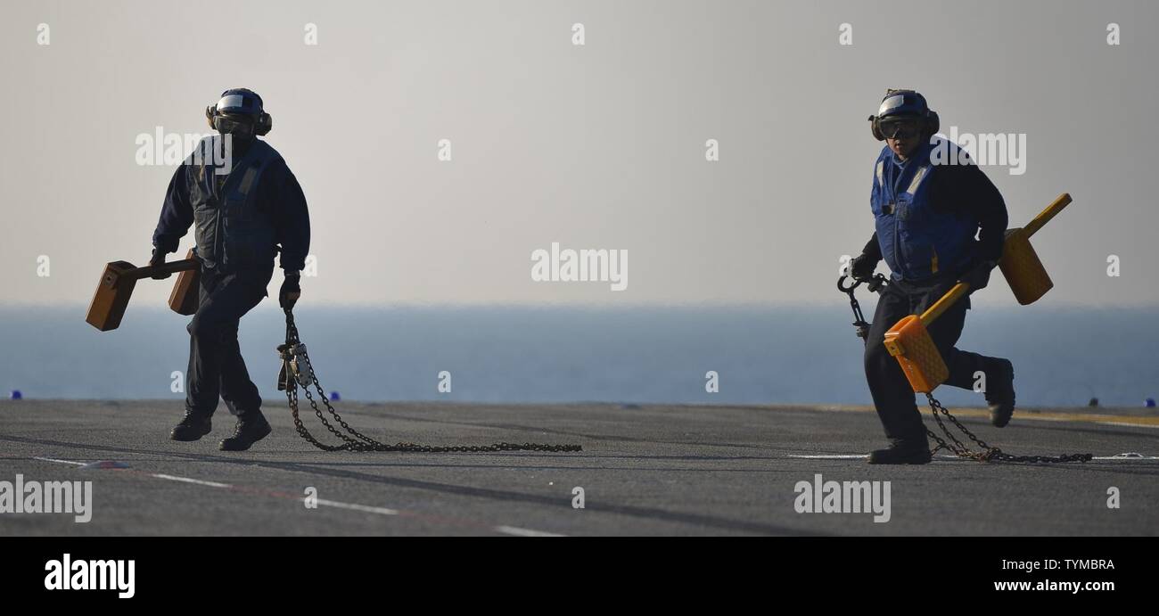 Atlantik (Nov. 16, 2016) - Segler Keile und Ketten entfernen als CH-53E Super Stallion, zugeordnet zu den Marine schweren Helikopter Squadron 464 (HMH-464), bereitet sich auf das Flight Deck der Amphibisches Schiff USS Iwo Jima (LHD7) nehmen. Iwo Jima vor kurzem ging nach New York in den Veteranen Woche New York City 2016 Teilnehmenden der Service für alle unsere Nation Veteranen zu ehren. Stockfoto