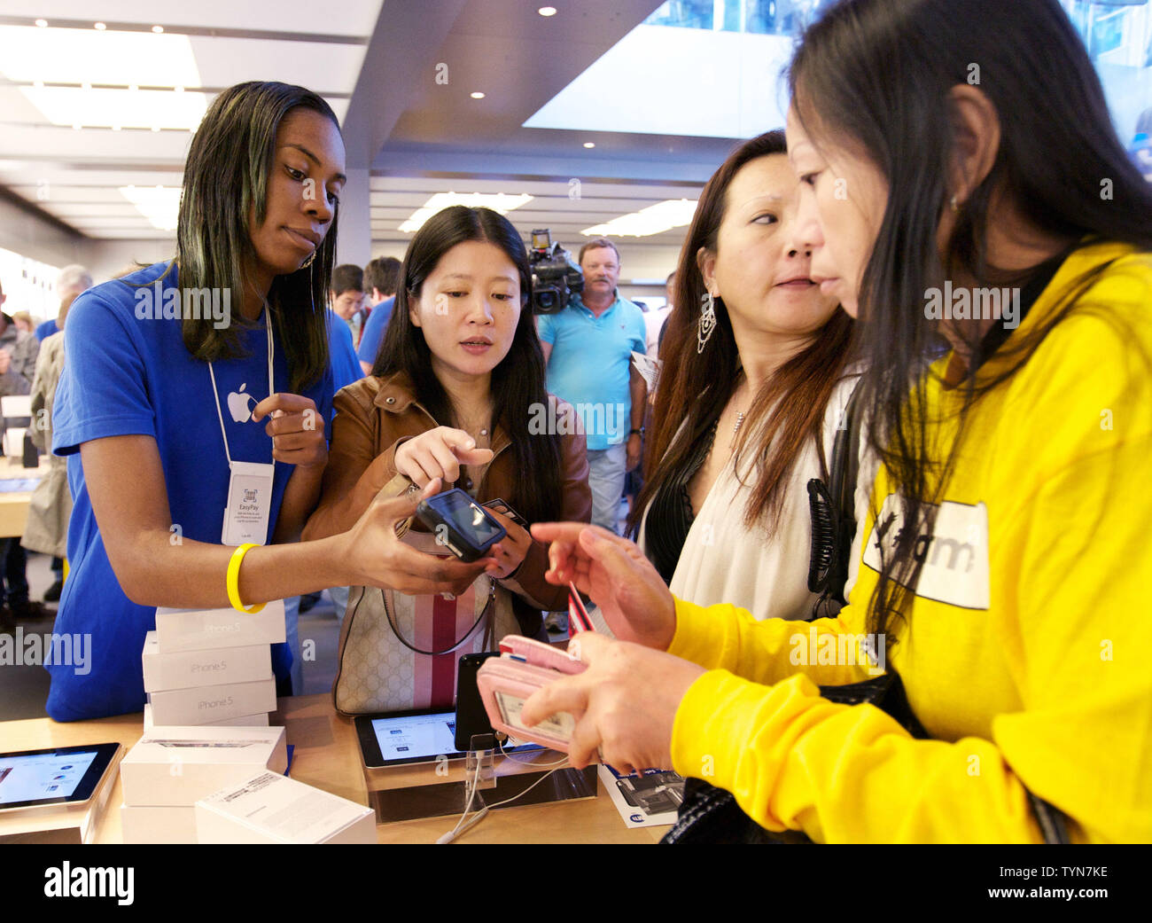 Ein Mitarbeiter (L) hilft seinen Kunden mit dem neuen iPhone 5, die zum Verkauf an der Apple Flagship Store in der Fifth Avenue haben am 21. September ging, 2012 in New York City. Die neue Version von Apples Smartphone verfügt über einen schlankeren Design, größeren Bildschirm und ein schnelleres Surfen beschleunigen. UPI/Monika Graff Stockfoto