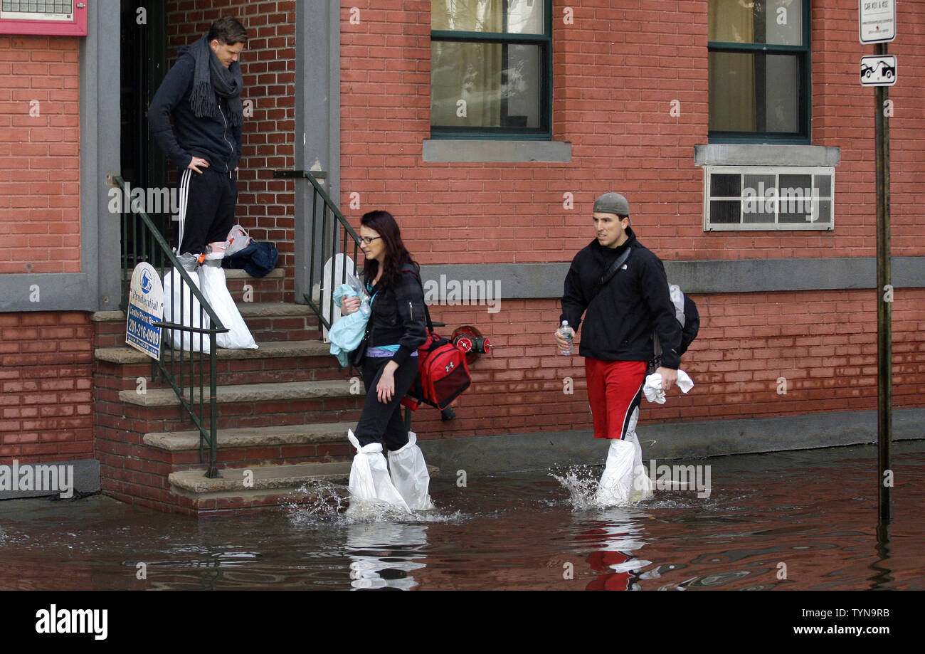 Menschen tragen Taschen durch die überfluteten Straßen einen Tag nach dem Hurrikan Sandstrand im Nordosten der Vereinigten Staaten in Hoboken, New Jersey am 31 Oktober, 2012 Hits. Die Wirkung der Sandstrand links große Teile von New York City und New Jersey mit Power und Mass Transit und der Beamten an Consolidated Edison sagte, es könnte bis zu einer Woche vor power ist vollständig restauriert. UPI/John angelillo Stockfoto