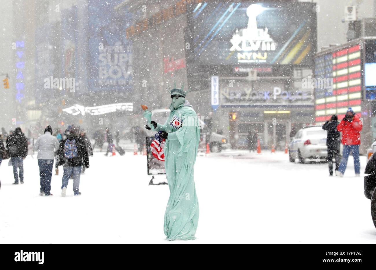 Ein Mann gekleidet wie die Freiheitsstatue und durch Beschilderung umgeben die Förderung der oben kommen Super Bowl sieht Bilder mit Touristen am Times Square in New York City am 21. Januar 2014 zu nehmen. New York City ist für eine zweite Polarwirbel im Jahr 2014 mit mehr kaltes Wetter und Schnee. UPI/John angelillo Stockfoto