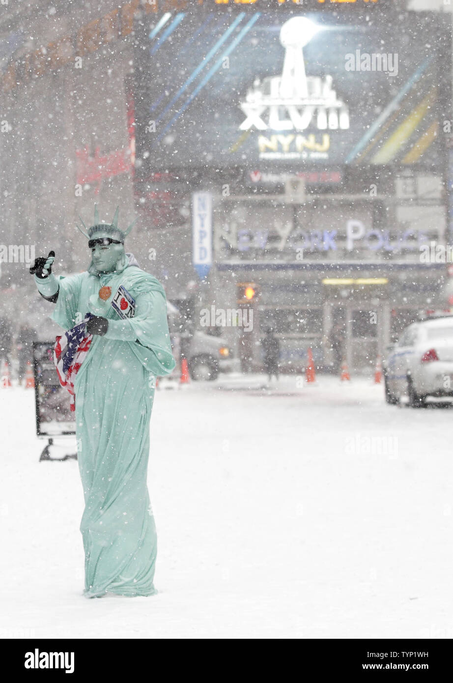 Ein Mann gekleidet wie die Freiheitsstatue und durch Beschilderung umgeben die Förderung der oben kommen Super Bowl sieht Bilder mit Touristen am Times Square in New York City am 21. Januar 2014 zu nehmen. New York City ist für eine zweite Polarwirbel im Jahr 2014 mit mehr kaltes Wetter und Schnee. UPI/John angelillo Stockfoto