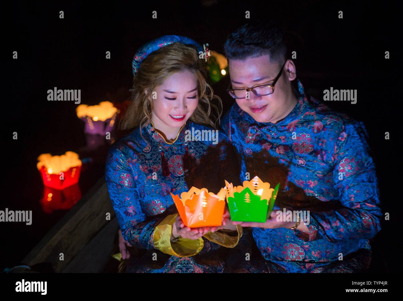 Vietnamesische paar Laternen Holding vor Ihnen droping in den Fluss in Hoi An, Vietnam während der Hoi An Vollmond Laternenfest Stockfoto