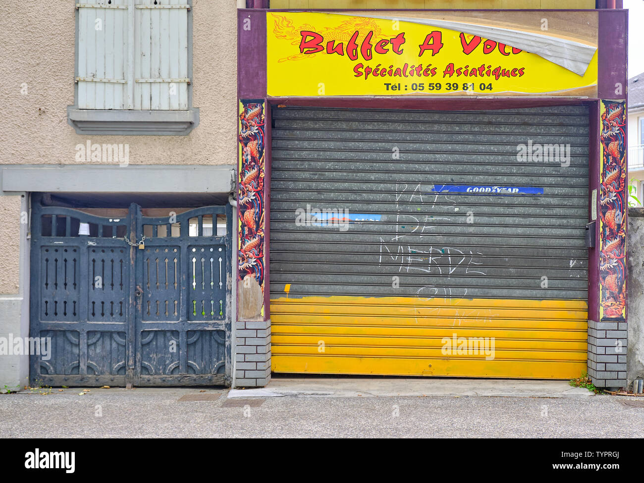 Pays de Merde" Graffiti auf Metall Tür der asiatischen Restaurant in Oloron Sainte Marie, Frankreich Juni 2019 Stockfoto