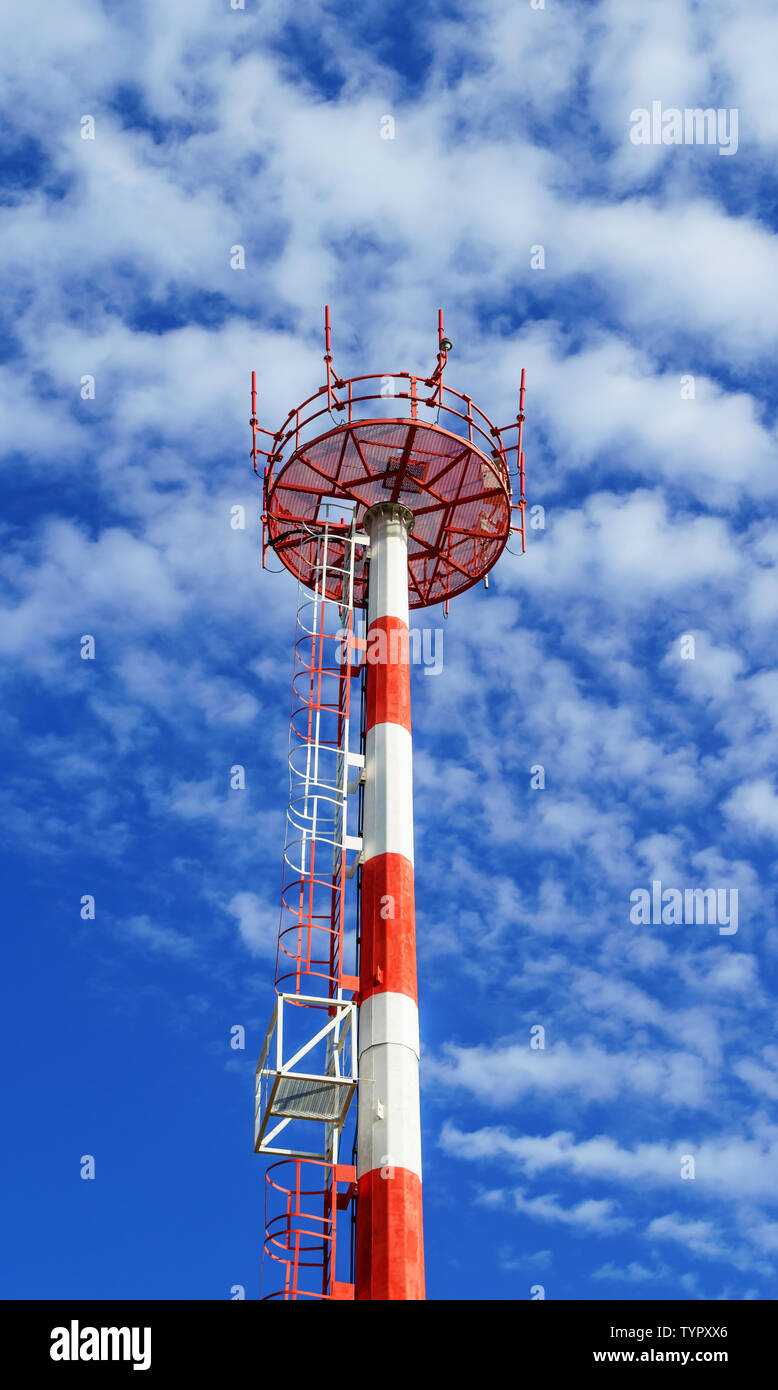 Telecom Tower für die drahtlose Übertragung von Radio, Handy oder Internet Signal. Telecom Mast in Rot und Weiß mit blauen Himmel und Wolken bemalt Stockfoto