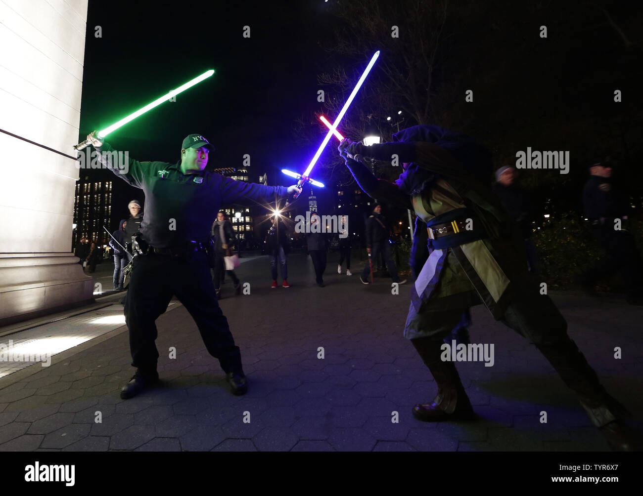 Eine NYPD Polizisten Zupacken 2 Lighsabers und genießt einen Moment mit Star Wars Film Fan, der in der jährlichen Lichtschwert Schlacht am Washington Square Park in New York City die Teilnahme ist am 18. Dezember 2015. 'Star Wars: The Force weckt' fand in eine rekordverdächtige 57 Millionen $ an der US-Box Office für seine Vorschau Vorführungen auf Donnerstag Nacht. Foto von John angelillo/UPI Stockfoto