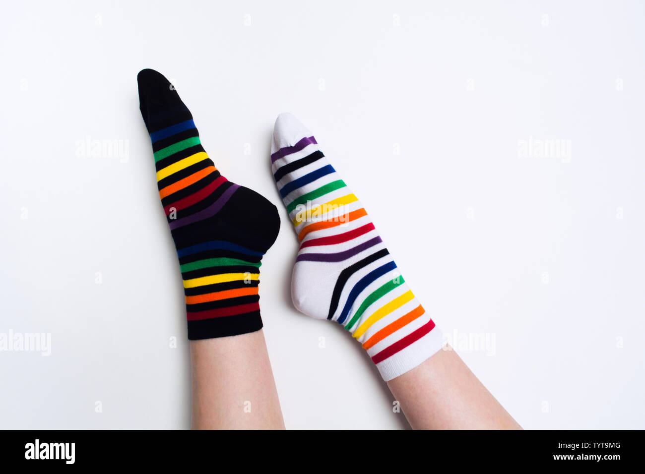 Frau Beine tragen lustig Helle verschiedene Gestreifte farbenfrohe Socken auf weißem Hintergrund mit kopieren. Flach. Ansicht von oben. Schwarz und Weiß Textil clot Stockfoto