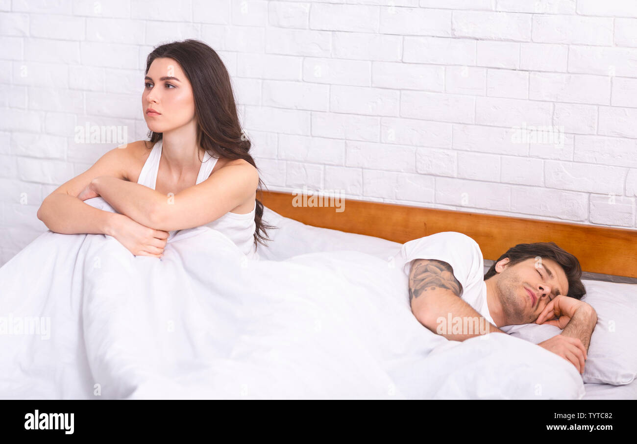 Unglückliche junge Frau mit Schlafstörungen im Bett sitzen Stockfoto