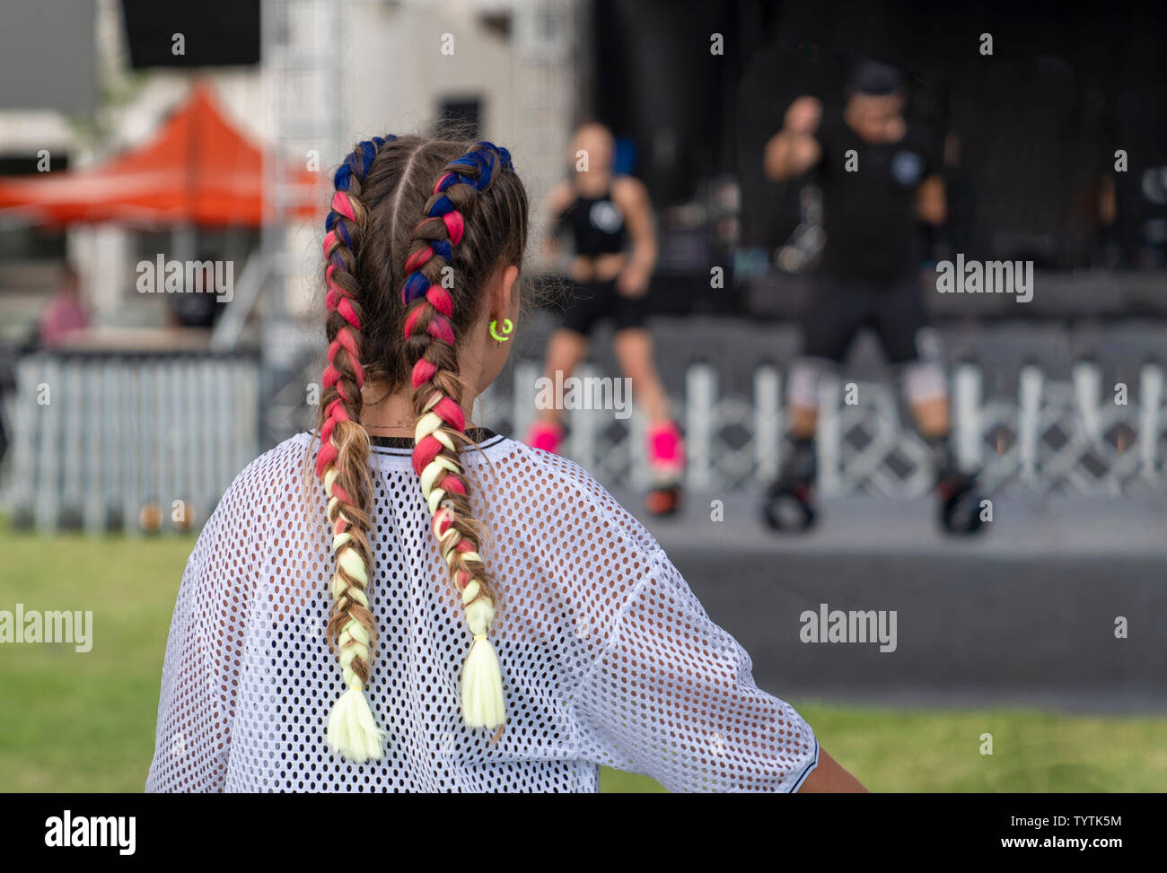 Rückansicht eines Mädchens mit schönen bunten Kanekalon beobachten eine Tanzshow Langzeitmiete. Stockfoto