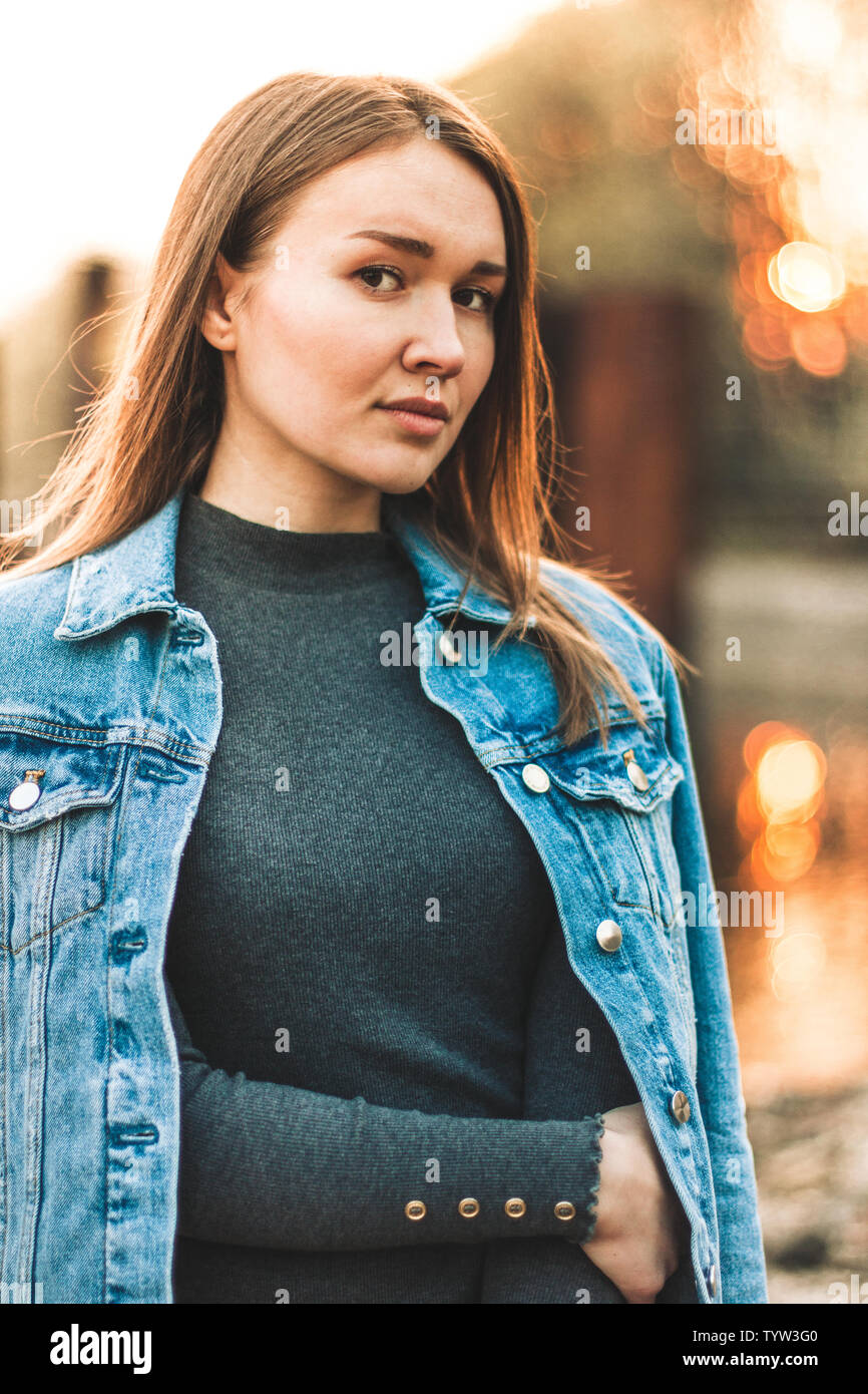 Portrait der Attraktive, schlanke, schöne junge Kaukasier blondes Mädchen in einer Jeans Jacke. Lächelnde Mädchen schönen warmen sunner Wetter gegen die Stockfoto