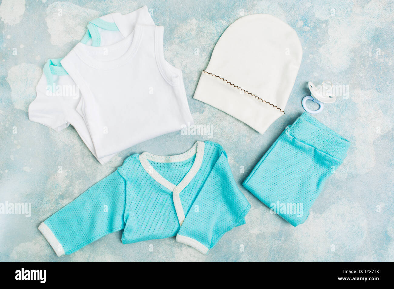 Neugeborenes Baby Kleidung - Weiße Strampler, blau Shirt, blau Hose, weißem Hut und Schnuller auf Blau strukturierten Hintergrund. Baby Konzept Dusche für Party Stockfoto