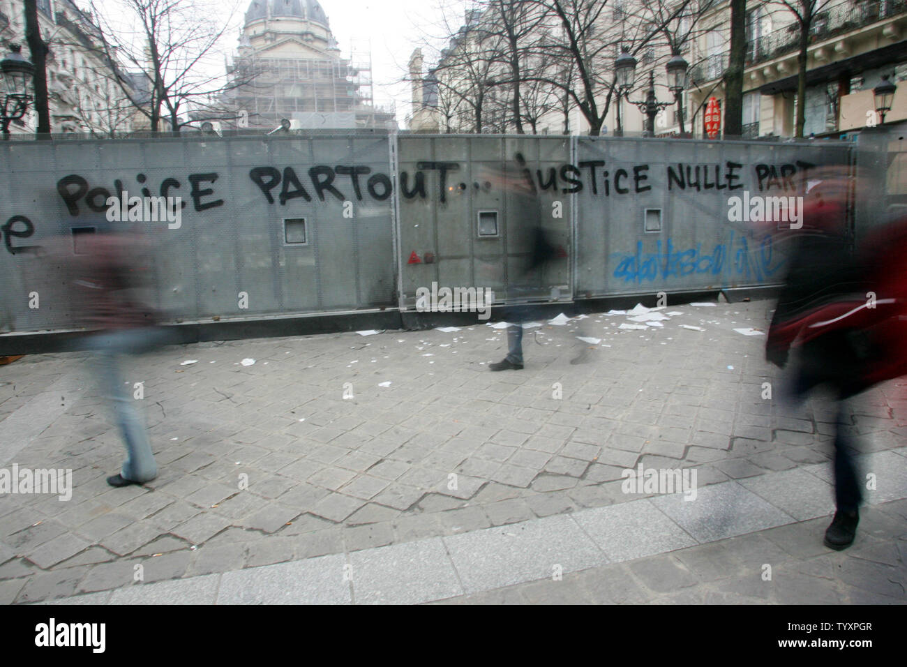 Menschen gehen vorbei an einer Polizei Barrikade versperrt den Eingang an der Sorbonne in Paris und das Lager ein Graffiti, das liest: "Die Polizei überall... Gerechtigkeit Nirgendwo" 21. März 2006. Französische Studenten und Gewerkschaften haben den Druck auf die Regierung verstärkt, fordert ein Tag der Demonstrationen und Streiks 28. März einen hart umkämpften neues Arbeitsrecht zu kämpfen. (UPI Foto/Eco Clement) Stockfoto