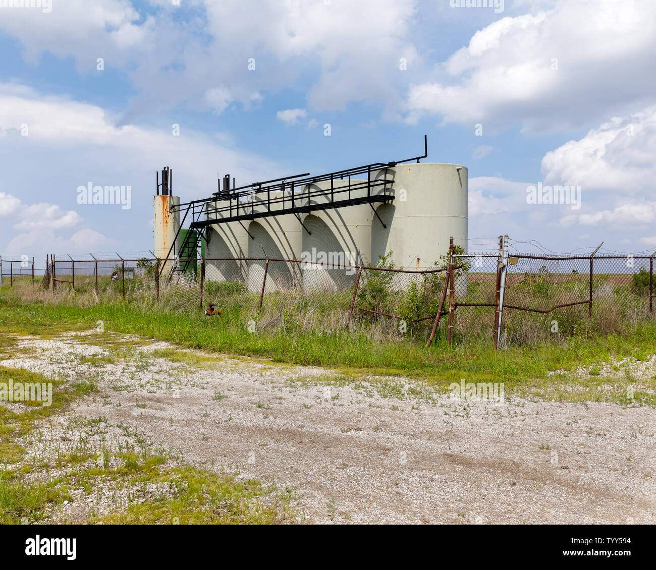 Alte Ölwannen-Lagertanks auf dem Feld der Farm. Verzicht auf Ölbrunnen, Umweltverschmutzung und Konzept der Ölförderung Stockfoto