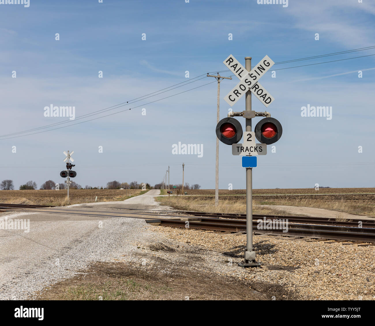 Bahnübergang mit Warnzeichen und Kontrolllampen auf einer Landstraße in der Landschaft Stockfoto
