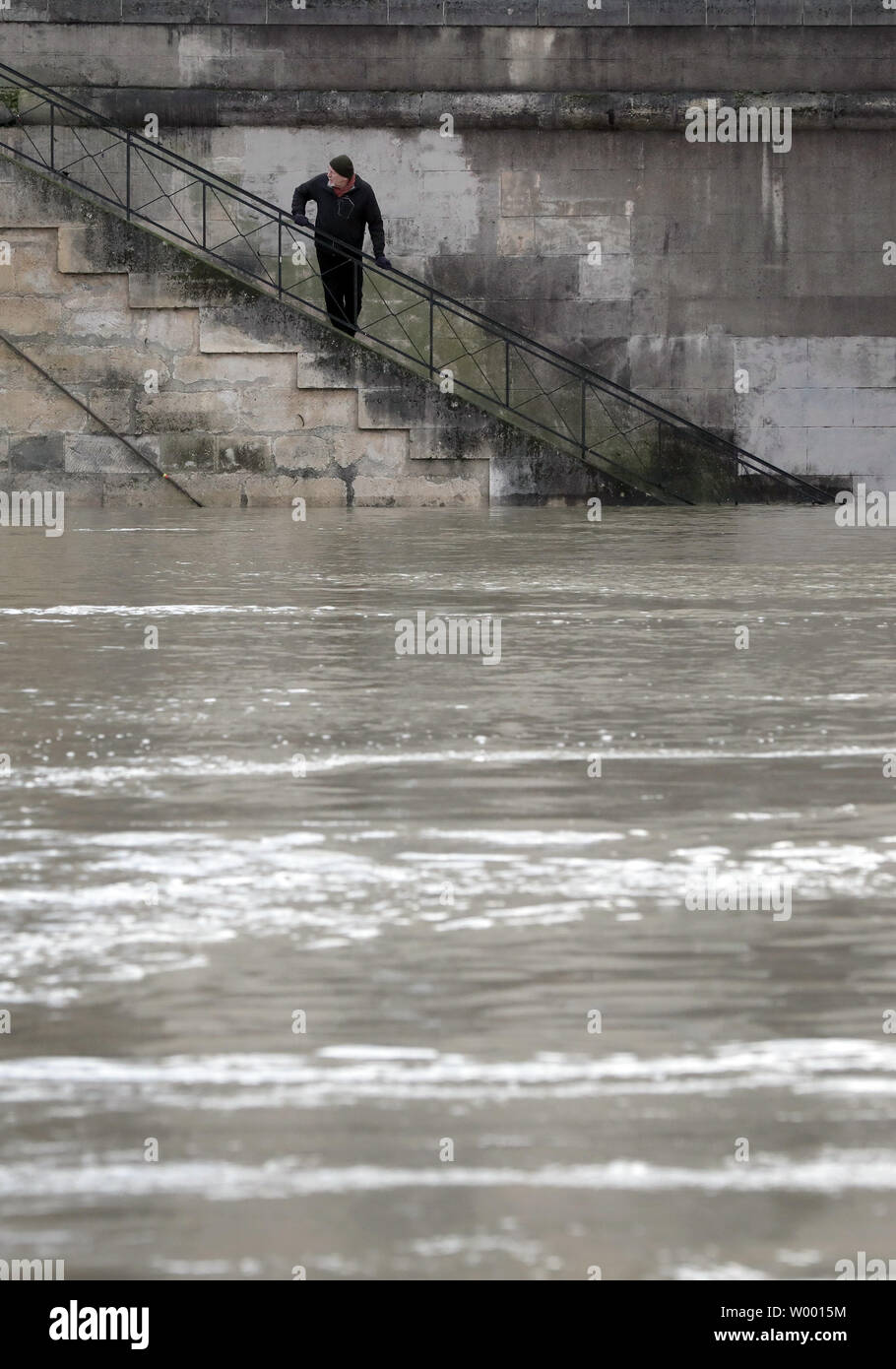 Ein Bewohner überprüft die geschwollenen Wasser des Flusses Seine folgenden sintflutartigen Regenfällen in Paris am 27. Januar 2018. Die französische Hauptstadt blieb auf Flood Alert nach dem Fluss seine Banken Burst, Verlassen Straßen überflutet und zwingen Teil der unteren Ebene der berühmte Louvre zu schließen. Foto von Maya Vidon-White Stockfoto