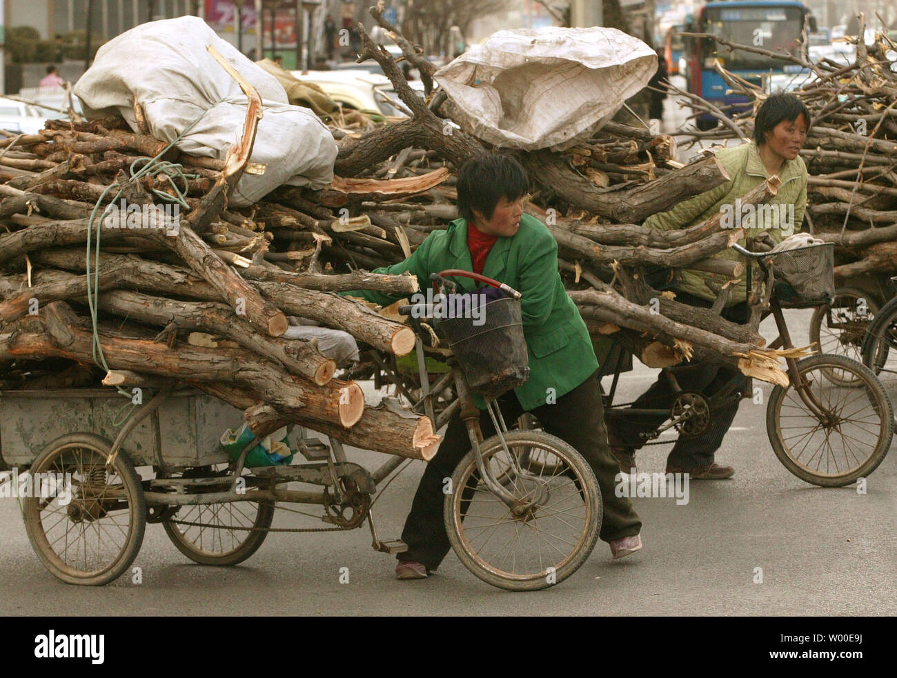 Migrant chinesische Frauen kämpfen um ihre Überladenen "TRISHAWS' durch einen Schnittpunkt in der Innenstadt von Peking, 13. März 2006. Aufgrund der fehlenden Arbeitsplätze in der Landschaft stetig ländlichen, städtischen Migration mit schätzungsweise 100 bis 150 Millionen Menschen in Bewegung. Obwohl die Bewegung offiziell immer noch verpönt ist, wie sie in Slums und städtischen Unruhen führen könnte, die wirtschaftlichen Vorteile gewonnen werden sind zur Kenntnis genommen worden. Überweisungen nach Hause geschickt haben sich die lokale Wirtschaft gestärkt. (UPI Foto/Stephen Rasierer) Stockfoto