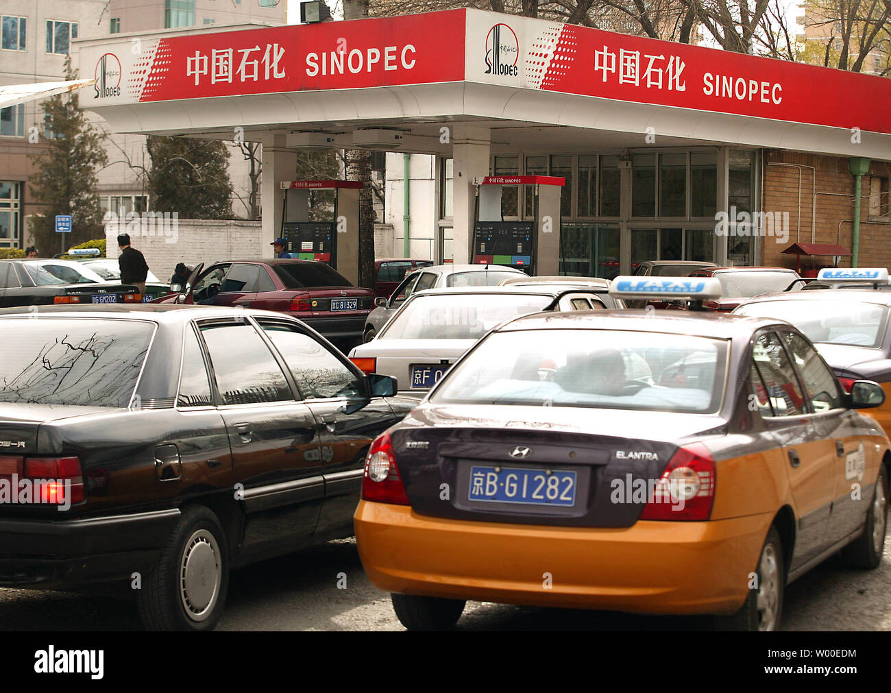 Ein tankwart füllt den Tank eines Autos als andere Autos in Linie an einer Tankstelle in der Innenstadt von Peking warten, 27. April 2006. Chinas hohen Verbrauch von Energie hat Besorgnis ausgelöst. Entsprechend einer nationalen Leitlinie im Jahr 2004 von der Nationalen Kommission für Entwicklung und Reform (NDRC), die Chinas Energieverbrauch 3.1 mal Durchschnitt der Welt wurde pro Einheit des BIP im Jahr 2002 freigegeben. Die Vereinigten Staaten sind der größte Verbraucher von Erdöl in der Welt von heute, aber China hat schnellste Rate der Welt des Wachstums in Öl verwenden. Eine Gallone 93 Oktan gas kostet $ 2.20. (UPI Foto/Stephen Rasierer) Stockfoto