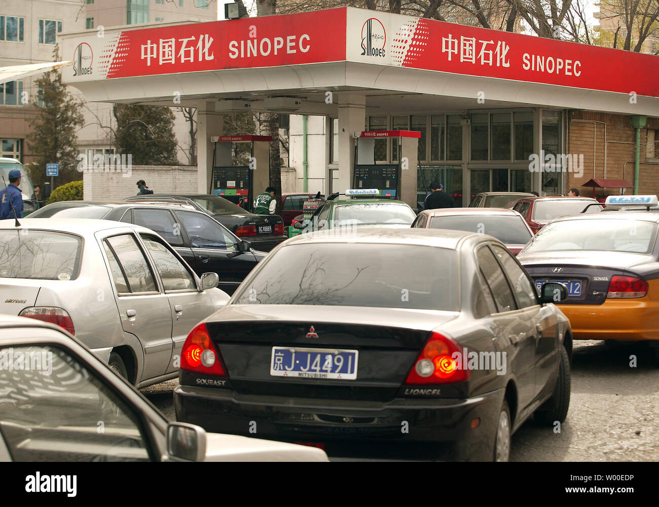Ein tankwart füllt den Tank eines Autos als andere Autos in Linie an einer Tankstelle in der Innenstadt von Peking warten, 27. April 2006. Chinas hohen Verbrauch von Energie hat Besorgnis ausgelöst. Entsprechend einer nationalen Leitlinie im Jahr 2004 von der Nationalen Kommission für Entwicklung und Reform (NDRC), die Chinas Energieverbrauch 3.1 mal Durchschnitt der Welt wurde pro Einheit des BIP im Jahr 2002 freigegeben. Die Vereinigten Staaten sind der größte Verbraucher von Erdöl in der Welt von heute, aber China hat schnellste Rate der Welt des Wachstums in Öl verwenden. Eine Gallone 93 Oktan gas kostet $ 2.20. (UPI Foto/Stephen Rasierer) Stockfoto