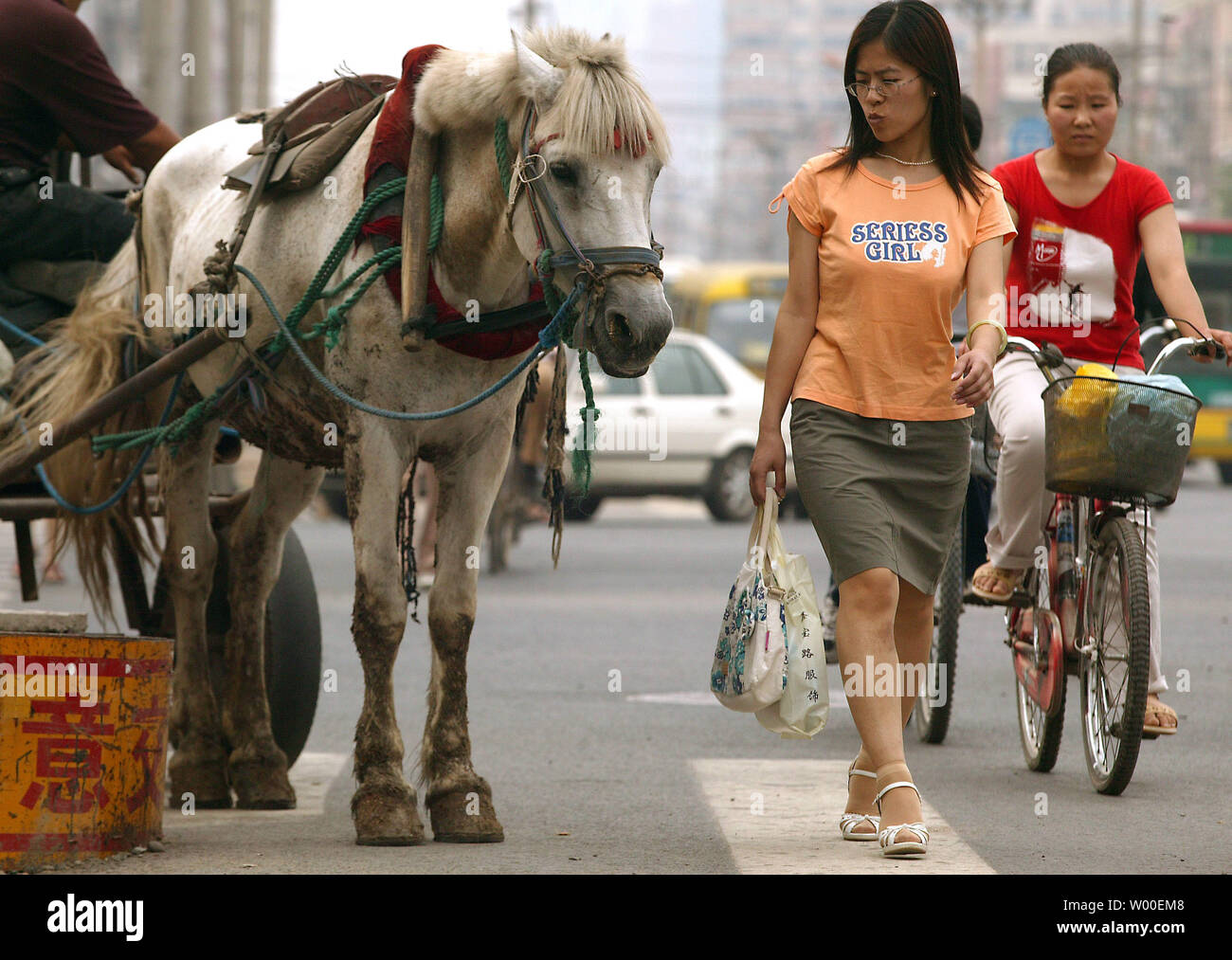 Eine chinesische Frau geht hinter einem Pferd ziehen einen Wagen von Obst zum Verkauf im Zentrum von Peking, China, am 22. Juni 2006, Peking, wie viele der wichtigsten Städte Chinas, ist eine lebendige Geschichte aus zwei Städten; eine Stadt offensiv Drängen auf eine Zukunft, High-Tech-Metropole, aber immer noch sehr viel, eine Stadt mit viel von seiner low-tech Vergangenheit. (UPI Foto/Stephen Rasierer) Stockfoto