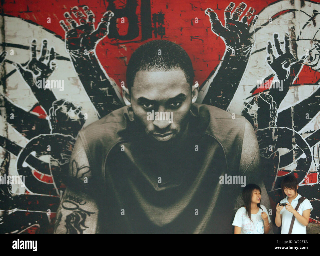 Zwei chinesische Mädchen hang-out außerhalb eines US-amerikanischen Sport Shop mit einem Bild von einer der NBA-Superstars, in der Innenstadt von Peking, 20. August 2006. Pekings Jugend teilen sich den gleichen Wunsch wie die amerikanische Jugend der neuesten Mode zu tragen, entweder durch Musik Videos, Filme oder Sport Sterne gefördert. (UPI Foto/Stephen Rasierer) Stockfoto