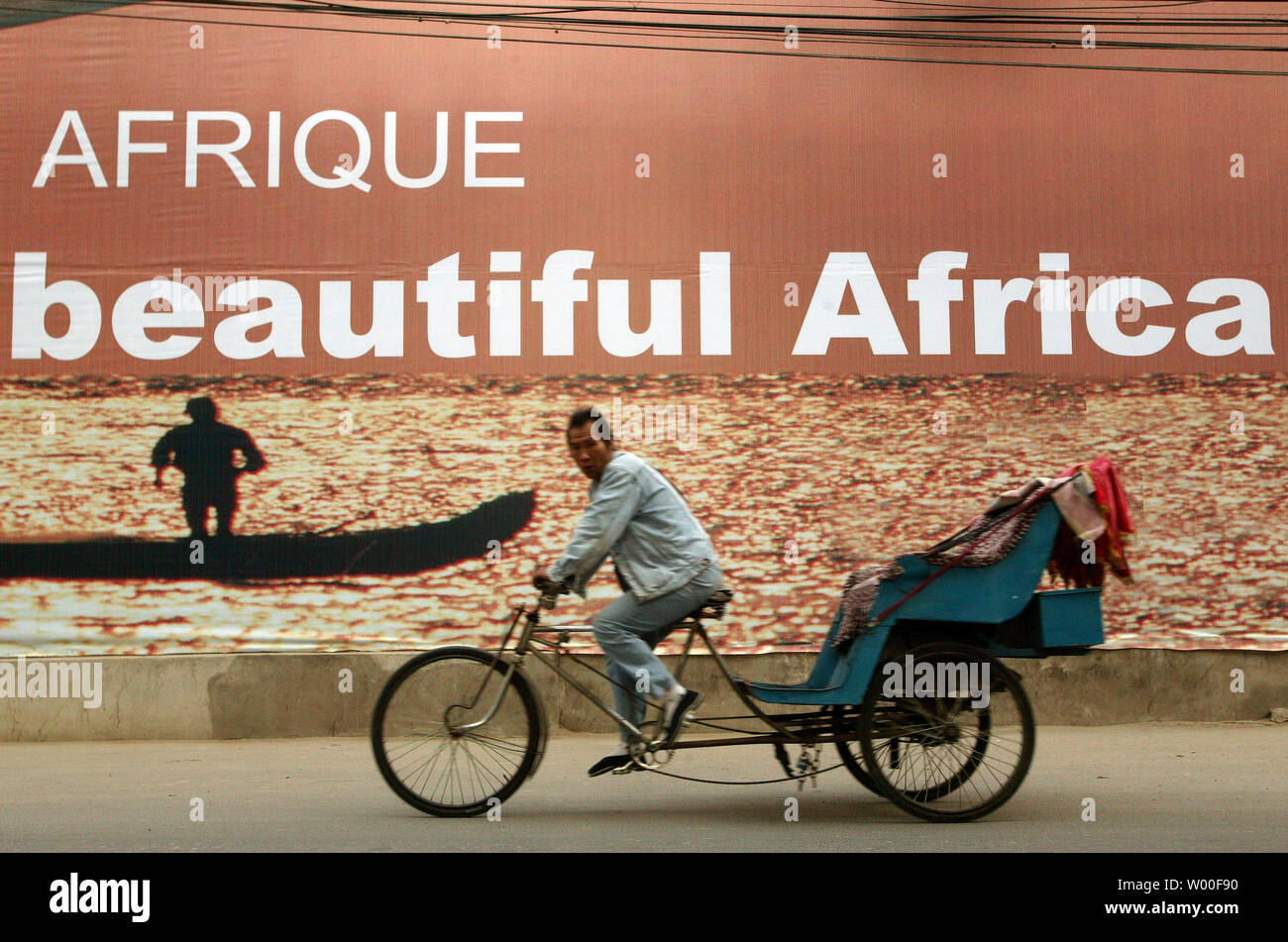 Ein chinesischer Mann peddles sein Tri-Kabine über eine einladende Werbung zu afrikanischen Delegierten für Chinas afrikanischen Gipfel in Peking, November 01, 2006 ankommen. China wird Gastgeber der Führer von über 40 afrikanische Nationen zu einem historischen Gipfel diese Woche, die wachsende diplomatische Macht des asiatischen Riesen Showcase und seine globale Suche nach natürlichen Ressourcen hervor. (UPI Foto/Stephen Rasierer) Stockfoto