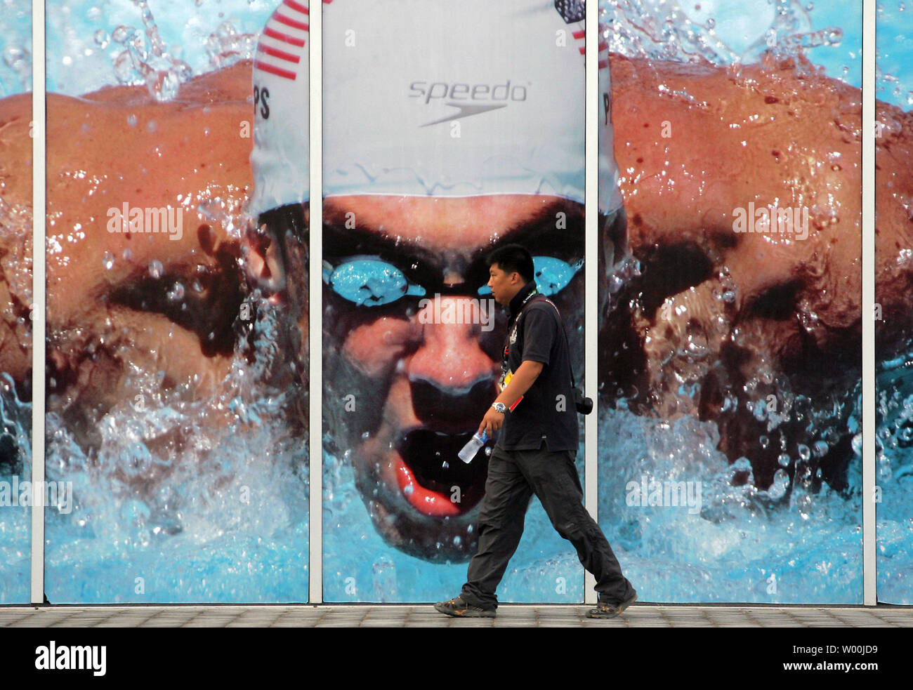 Ein chinesischer Journalist Wanderungen vorbei an einem riesigen Foto von American Gold - medaillenträger Schwimmer Michael Phelps auf dem Olympic Green, nur eine Woche vor der Eröffnungsfeier für die Spiele 2008 in Peking, August 01, 2008. (UPI Foto/Stephen Rasierer) Stockfoto