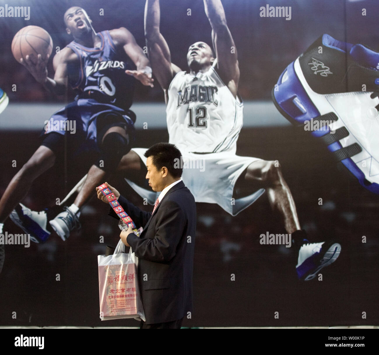 Ein chinesischer Mann hinter einem riesigen Adidas Reklametafeln, mit  NBA-Stars, die sich für ihre neue Linie der Basketball Schuhe in der  Innenstadt und Einkaufszentrum in Peking, 21. November 2008. Nach den  Statistiken