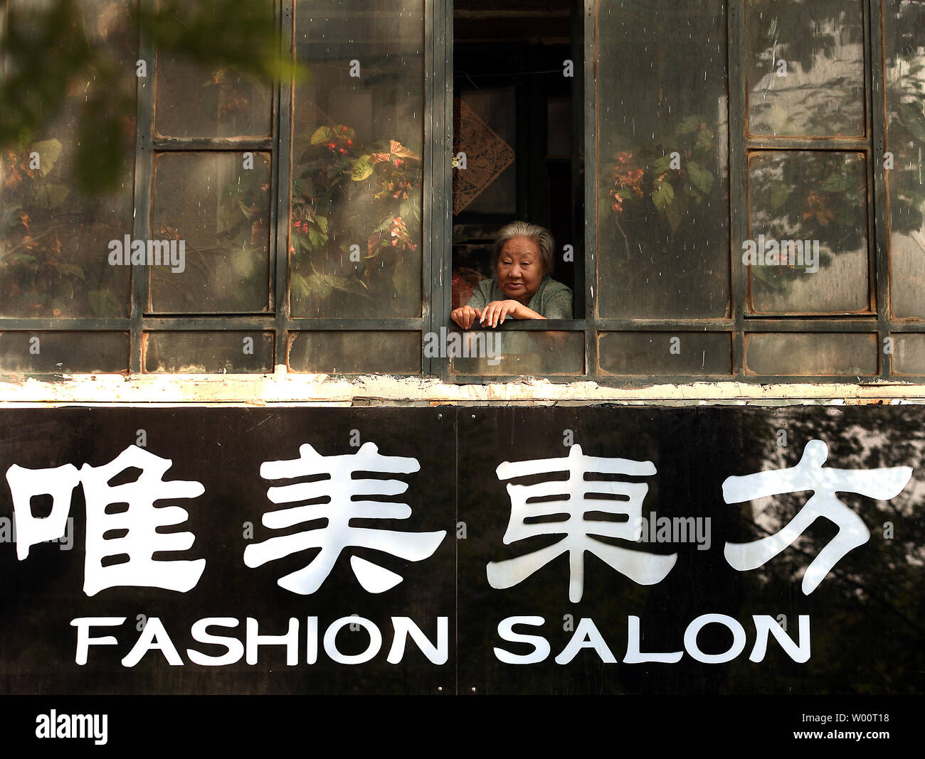 Eine ältere chinesische Frau schaut aus dem Fenster über eine trendige Bekleidungsgeschäft für junge Frauen in Peking, 11. September 2010. Der Anteil der Menschen über 65 in China wird übertreffen, die von Japan im Jahr 2030, das China der weltweit am meisten gealtert Gesellschaft machen, dass nach Angaben der chinesischen Akademie für Sozialwissenschaften. Das Problem mit einer Zunahme der älteren Bevölkerung Chinas ist, dass es langsam das Pro-Kopf-BIP Wachstum, Investitionen und Kapitalakkumulation, bei gleichzeitiger Erhöhung der öffentlichen Schulden. UPI/Stephen Rasierer Stockfoto