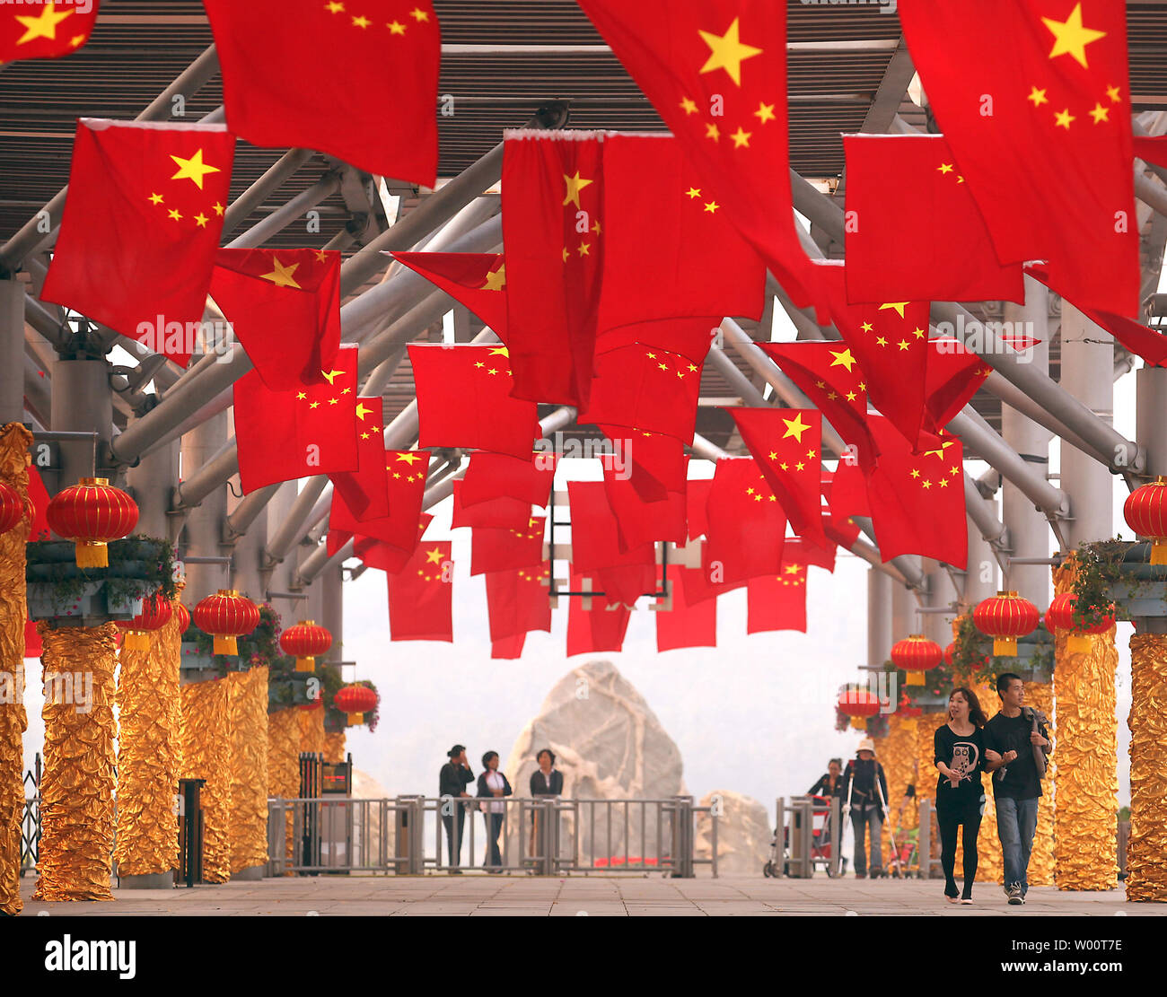 Chinesische Spaziergang unter Dutzende von nationalen Flaggen am Eingang zu einem Park in Peking am 30. September 2010. China müssen möglicherweise bis zu 24 Billionen Yuan (usd3.6 Billion) in die städtische Infrastruktur investiert bis 2020 die zunehmende Zahl der ländlichen Bevölkerung in die Städte unterzubringen, laut staatlichen Medien. UPI/Stephen Rasierer Stockfoto