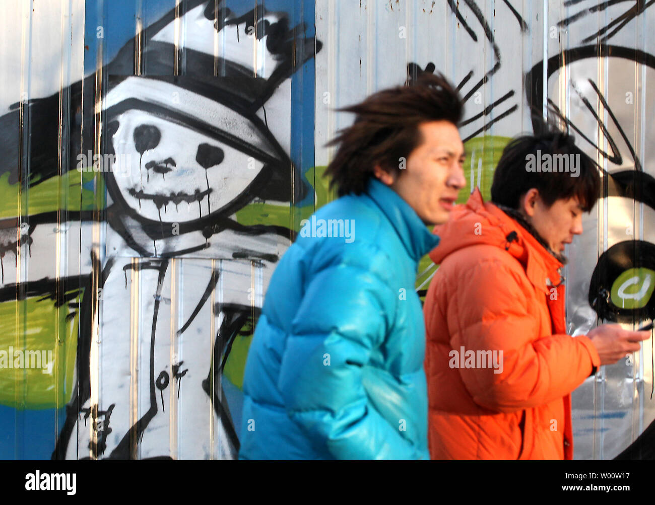 Chinesische Männer vorbei Street Graffiti, eine Vogelscheuche in Peking am 16. Januar 2011. Beide banden und Graffiti Künstler sind ein neues Problem für die Polizei in der Hauptstadt und die Bewohner der Stadt zu stellen, zunehmend "Verwestlicht". UPI/Stephen Rasierer Stockfoto