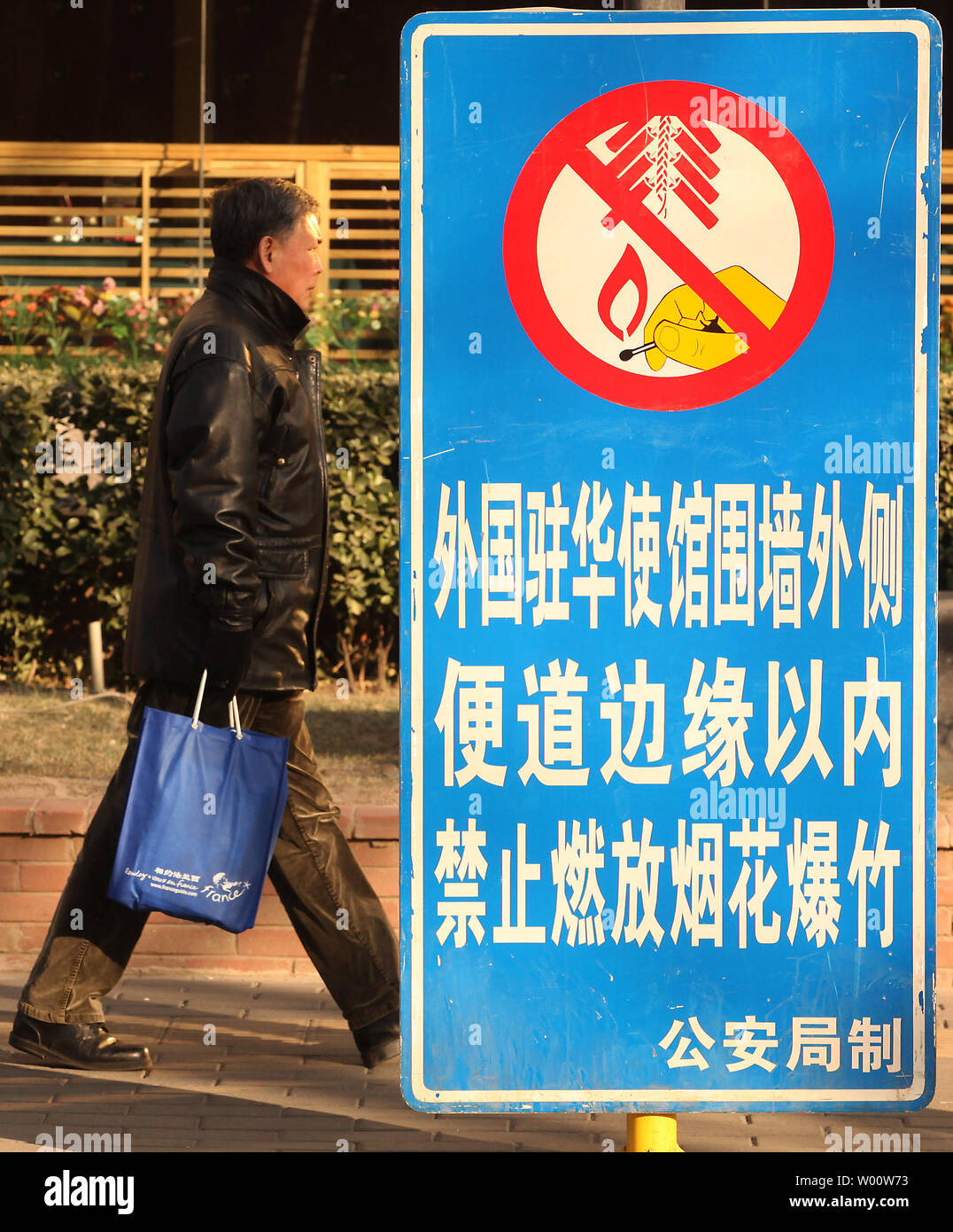 Ein chinesischer Mann hinter einem großen, seitlichen Straße - Warnschild Deklarieren der Bereich 'kein Feuerwerk "Zone in der Innenstadt von Beijing Februar 1, 2011. Das chinesische Neujahrsfest, der Mittwoch beginnt und dauert ca. zwei Wochen, wird täglich mit Feuerwerk gefeiert. Vor dem Hintergrund einer langen Dürre, Feuerwehrmänner haben auf roten Alarm gesetzt worden. UPI/Stephen Rasierer Stockfoto