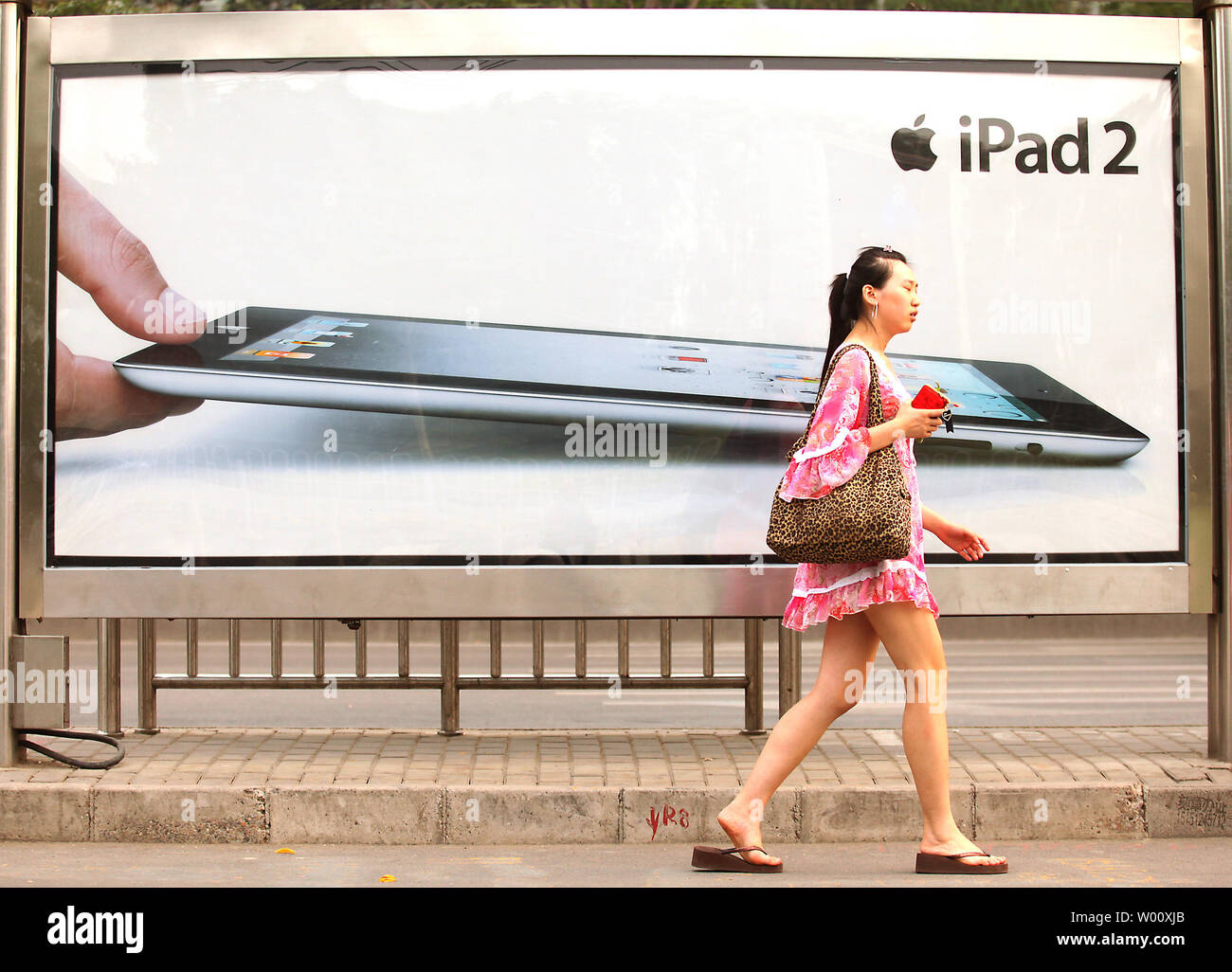 Eine chinesische Frau geht Vergangenheit einen Gehsteig Plakatwerbung die neue Apple iPad 2 nun auf Verkauf in Peking am 5. Juli 2011. Trotz des iPad 2 Klon Invasion in großen Städten Chinas, die echten iPad 2 bleibt sehr beliebt in China. Apple plant, seinen fünften Store im Land bis zum Ende des Jahres geöffnet. Die chinesischen Anbieter sind dem Vernehmen nach Kauf des iPad wird von Apple abgelehnt in iPad Klone zu verwenden. UPI/Stephen Rasierer Stockfoto