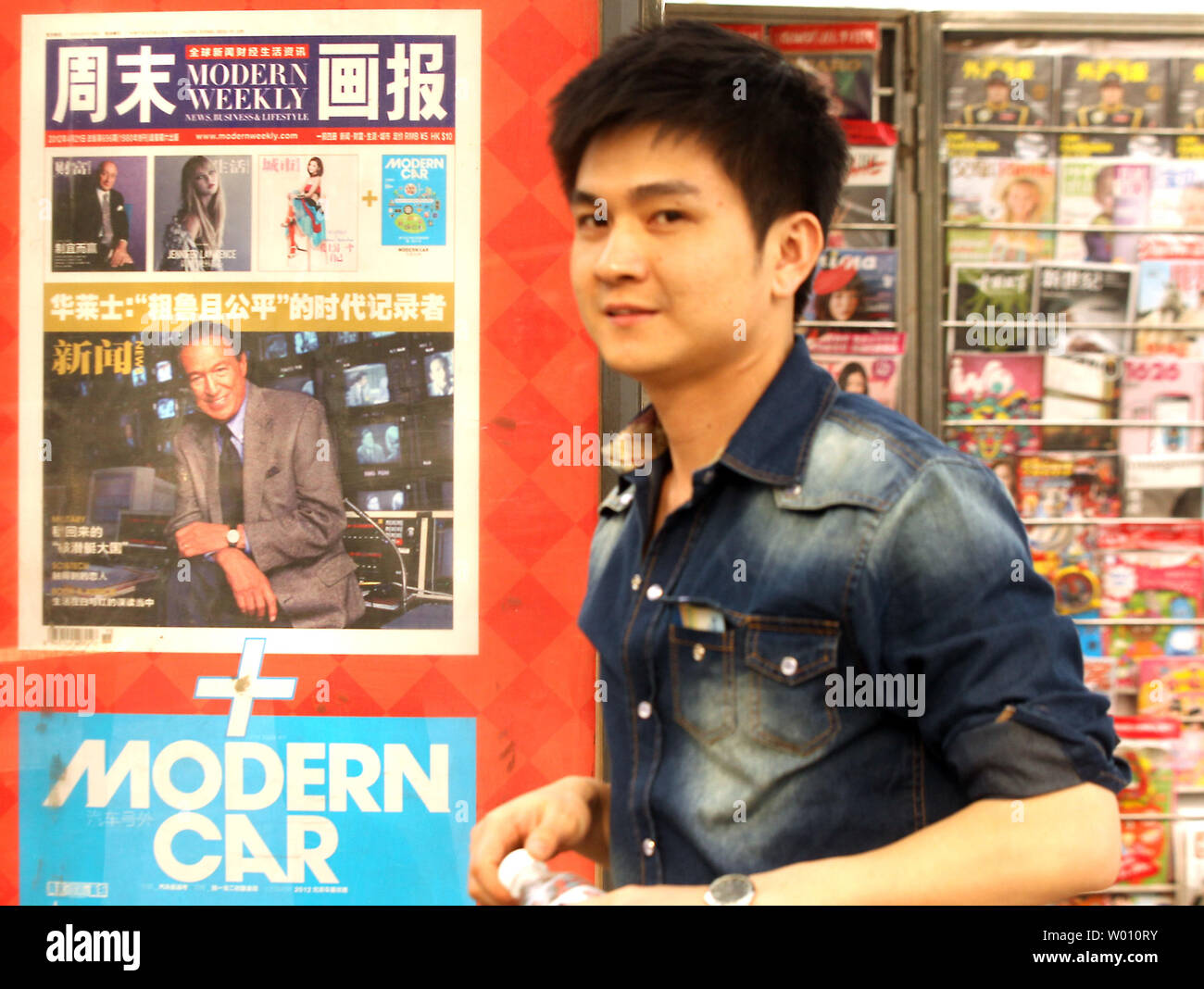 Ein chinesischer Mann hinter einem news Kiosk Anzeige eine Anzeige von einem der zentralen chinesischen Zeitungen, mit einem front-page Story über das Leben des berühmten amerikanischen Nachrichtensprecher Mike Wallace, in Peking am 30. April 2012. In einer ungewöhnlichen Bewegung durch die staatlichen Medien aufgrund der vorherrschenden Zensur, eine Geschichte auf der Maverick, amerikanischer Pionier in der Berichterstattung erschien auf der Titelseite einer der wichtigsten Zeitungen des Landes. UPI/Stephen Rasierer Stockfoto