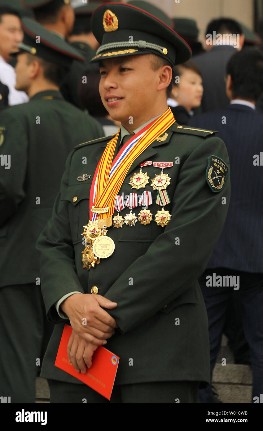 Ein junger Soldat wirft mit einer Truhe voller Medaillen und hielt seine rote Eintrittskarte der "Feier des 90. Jahrestages der Kommunistischen Jugendliga von China" in Peking am 4. Mai 2012 zu besuchen. Die jüngsten Ereignisse im Zusammenhang mit den Themen Menschenrechte und Korruption haben einige Zweifel an der Fähigkeit der Chinesischen Kommunistischen Partei einen festen Griff auf den Staatsapparat und die chinesische Gesellschaft zu pflegen, sowohl nach Akademikern und Analysten in China arbeiten. UPI/Stephen Rasierer Stockfoto